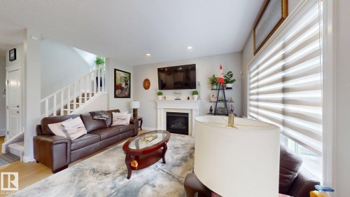 Living area featuring a fireplace with a white mantel, recessed lighting, and a window with horizontal blinds - 22407 99 Avenue Nw, Edmonton, AB 