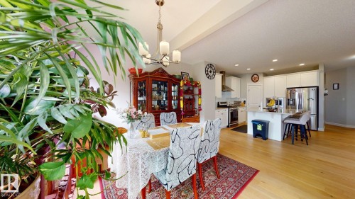 Hardwood flooring throughout, recessed lighting, and a kitchen featuring white cabinetry, a stainless steel refrigerator, and a kitchen island with seating - 22407 99 Avenue Nw, Edmonton, AB 