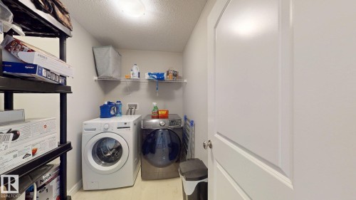 Utility area featuring a washer and dryer, wall-mounted shelving, and light-toned flooring - 22407 99 Avenue Nw, Edmonton, AB 