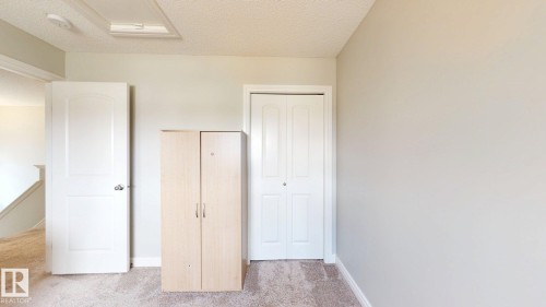 Carpeted flooring, light-colored walls, white interior door, and a built-in closet with bi-fold doors - 22407 99 Avenue Nw, Edmonton, AB 