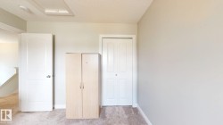 Carpeted flooring, light-colored walls, white interior door, and a built-in closet with bi-fold doors - 