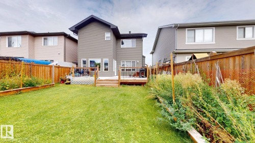 Expansive backyard featuring a large grass area, wood privacy fencing, a multi-level wood deck, and raised garden beds - 22407 99 Avenue Nw, Edmonton, AB 