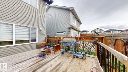 Rear wood-finish deck with black spindle railing, offering access to the property - 22407 99 Avenue Nw, Edmonton, AB 