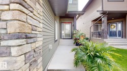 Stone veneer column, horizontal siding, covered entryway, concrete walkway, and landscaped planting - 