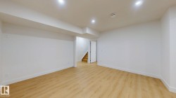 Spacious interior with neutral white walls, recessed ceiling lighting, and wood-finish flooring - 