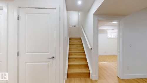 Wood-finish flooring throughout, white walls, wood staircase with white railing, recessed lighting, and white interior doors - 22407 99 Avenue Nw, Edmonton, AB 
