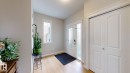Entryway featuring wood-finish flooring, a white paneled closet, and a front door with decorative glass inserts - 22407 99 Avenue Nw, Edmonton, AB 