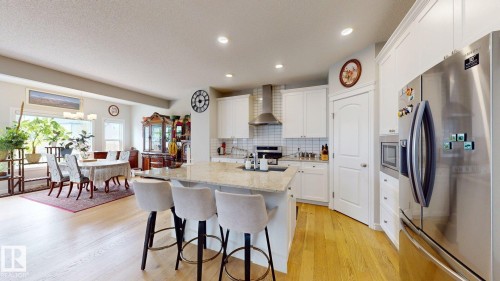 Kitchen island with light-toned countertop, stainless steel appliances, white cabinetry, and wood-finish flooring - 22407 99 Avenue Nw, Edmonton, AB 