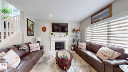 Fireplace with a white mantel, recessed lighting, white baluster staircase, and large window with horizontal blinds - 22407 99 Avenue Nw, Edmonton, AB 