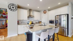 Kitchen featuring white cabinetry, light wood-finish flooring, a center island with a light-toned countertop, and stainless steel appliances - 