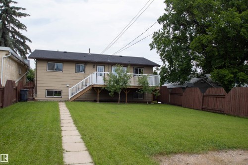 Expansive rear yard featuring a stone pathway, mature trees, and a wooden privacy fence - 4725 45 Ave, St. Paul Town, AB - Outdoor With Deck Patio Veranda