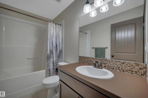 Full vanity mirror, integrated sink, mosaic tile backsplash, and a shower-over-tub combination - 12903 205 Street Nw, Edmonton, AB 