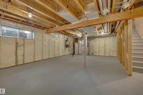Unfinished basement space featuring exposed wooden joists, framed walls with insulation, a concrete floor, and a utility window - 12903 205 Street Nw, Edmonton, AB 
