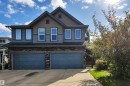 Stone and siding exterior with dual garage doors, concrete driveway, and established landscaping - 12903 205 Street Nw, Edmonton, AB 