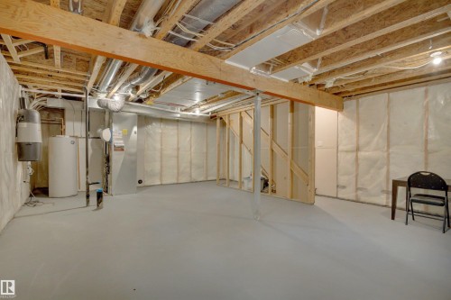 Unfinished basement featuring exposed wood joists, structural wood beams, and a water heater - 12903 205 Street Nw, Edmonton, AB 