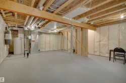 Unfinished basement featuring exposed wood joists, structural wood beams, and a water heater - 