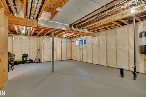Unfinished basement featuring exposed wood joists, insulated walls, concrete flooring, and a small window - 12903 205 Street Nw, Edmonton, AB 