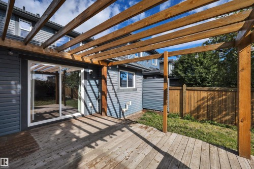 Expansive wood deck with a pergola, featuring a sliding glass door, durable siding, and a wooden privacy fence - 12903 205 Street Nw, Edmonton, AB 