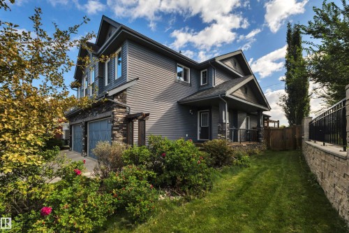 Exterior featuring dark gray siding, stone accents, two-car garage, and a covered porch - 12903 205 Street Nw, Edmonton, AB 