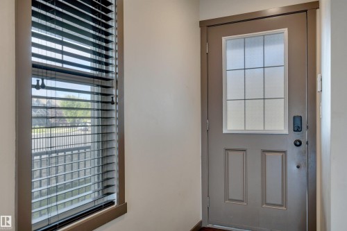 Entry door with frosted glass panel and dark hardware, complemented by a tall window with horizontal blinds - 12903 205 Street Nw, Edmonton, AB 