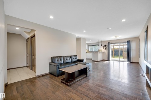 Expansive living area featuring rich wood-finish flooring, recessed lighting, and a sliding glass door to the exterior - 12903 205 Street Nw, Edmonton, AB 