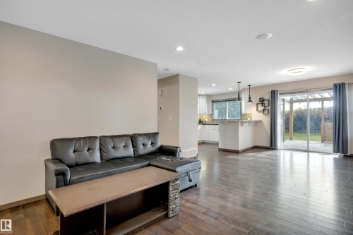 Recessed lighting, wood-finish flooring, sliding glass door, white cabinetry, and a kitchen island with pendant lighting - 12903 205 Street Nw, Edmonton, AB 