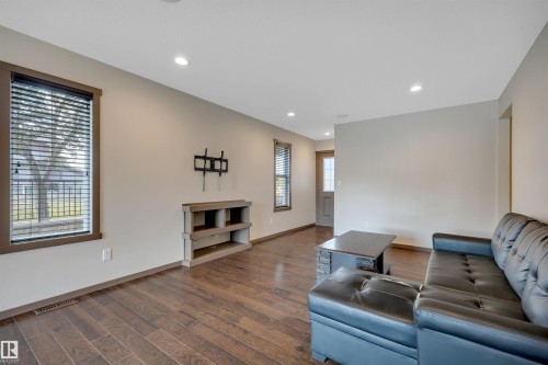 Recessed lighting, wood-finish flooring, built-in media console, and a door with frosted glass paneling - 12903 205 Street Nw, Edmonton, AB 
