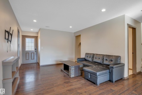 Spacious living area featuring wood-finish flooring, recessed lighting, and a transom-style entry door with divided lites - 12903 205 Street Nw, Edmonton, AB 