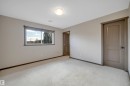 Neutral-toned carpet flooring, a window offering natural light, and a flush-mount ceiling light fixture - 12903 205 Street Nw, Edmonton, AB 