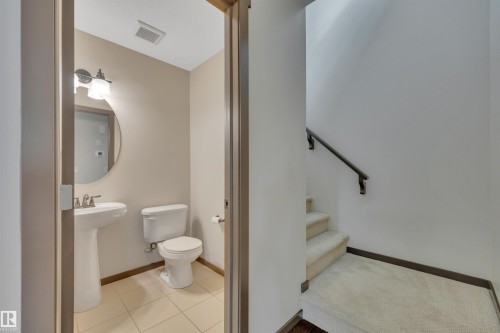 Powder room with pedestal sink, round mirror, and tile flooring - 12903 205 Street Nw, Edmonton, AB 