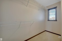 Integrated wire shelving system, neutral wall paint, window with blinds, carpeted flooring - 