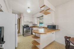 Kitchen featuring white cabinetry, stainless steel range, wood-finish countertops, and an integrated breakfast bar with shelving - 