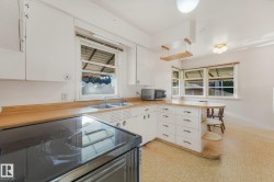 Kitchen featuring white cabinetry, wood-finish countertops, dual basin sink, and multiple windows - 