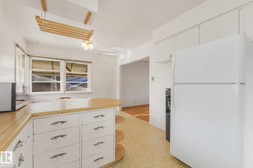 Kitchen featuring wood-finish countertops, white cabinetry with chrome hardware, and an integrated ceiling light fixture - 11507 135 Street Nw, Edmonton, AB 
