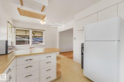 Kitchen featuring wood-finish countertops, white cabinetry with chrome hardware, and an integrated ceiling light fixture - 