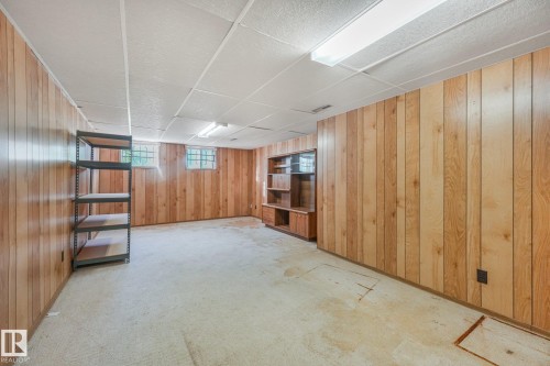 Paneled walls with a built-in shelving unit, drop ceiling with fluorescent lighting, and two glass block windows - 11507 135 Street Nw, Edmonton, AB 