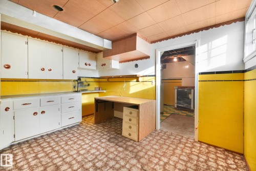 White cabinetry, yellow tiled walls, patterned floor covering, wood-finish ceiling, and a built-in desk - 11507 135 Street Nw, Edmonton, AB 