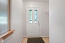 Bright entryway featuring a white six-panel door with decorative glass inserts, wood-finish flooring, and neutral wall finishes - 11507 135 Street Nw, Edmonton, AB 
