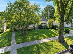 Manicured front lawn with mature trees, established landscaping, and a concrete pathway leading to the entry - 