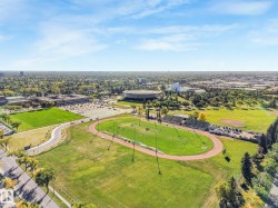 Aerial perspective of a sprawling urban landscape featuring a sports complex with a running track, a baseball diamond, and a large stadium structure - 