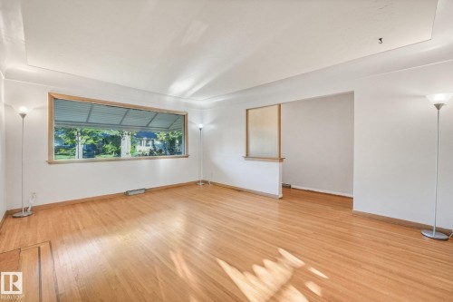 Hardwood flooring, expansive window, tray ceiling, recessed wall feature, and an open doorway - 11507 135 Street Nw, Edmonton, AB 