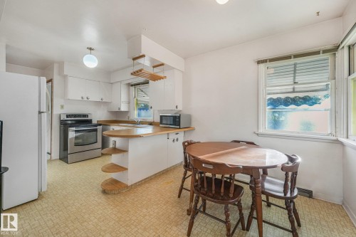 Kitchen featuring white cabinetry, stainless steel range, wood-finish countertops, and an integrated dining counter - 11507 135 Street Nw, Edmonton, AB 