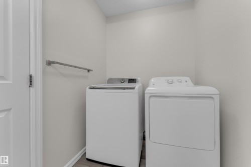 Dedicated laundry area with a white door, light-colored walls, and wood-finish flooring - 2912 31 Street Nw, Edmonton, AB 