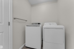 Dedicated laundry area with a white door, light-colored walls, and wood-finish flooring - 