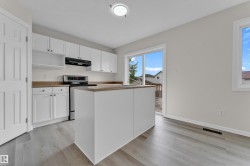 Kitchen with white cabinetry, stainless steel range, and a central island - 