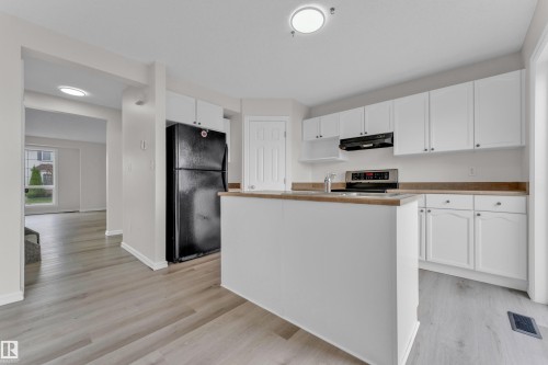 Kitchen featuring white cabinetry, light wood-finish countertops, stainless-steel range, and a central island - 2912 31 Street Nw, Edmonton, AB 