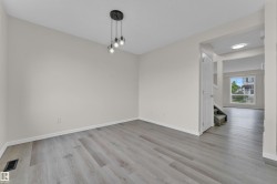 Spacious room featuring wood-finish flooring and a contemporary three-light chandelier - 