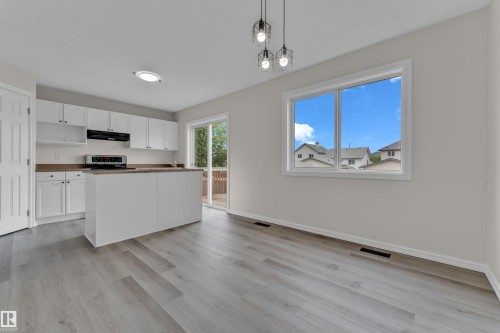 Kitchen with white cabinetry, stainless steel appliances, wood-finish countertops, and a central island - 2912 31 Street Nw, Edmonton, AB 