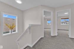 Upper-level landing with plush gray carpeting, white walls, and recessed lighting - 