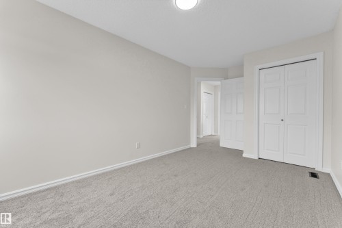 Neutral wall color, light gray carpeting, white trim, and white bi-fold closet doors - 2912 31 Street Nw, Edmonton, AB 